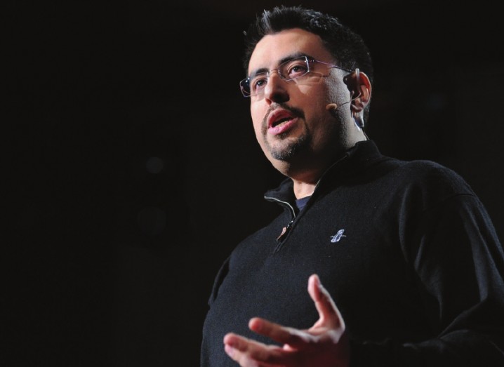 Man in black jumper speaking on a stage.