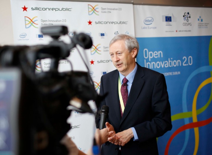 Martin Curley (a man in a dark suit with grey hair) is interviewed on camera in front of a white and blue banner that says Open Innovation 2.0.