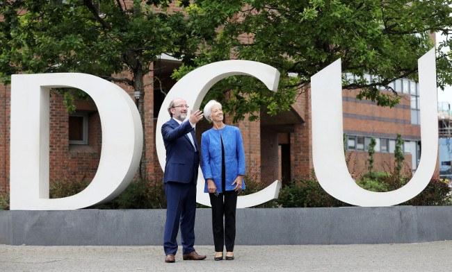 Prof Brian MacCraith standing with Christine Lagarde in front of DCU logo