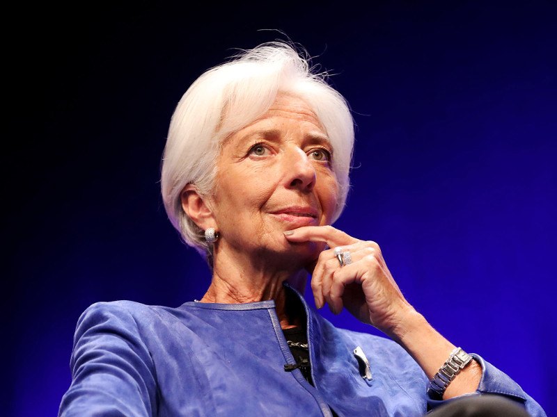 christine lagarde wearing royal blue jacket with finger under chin in pensive pose
