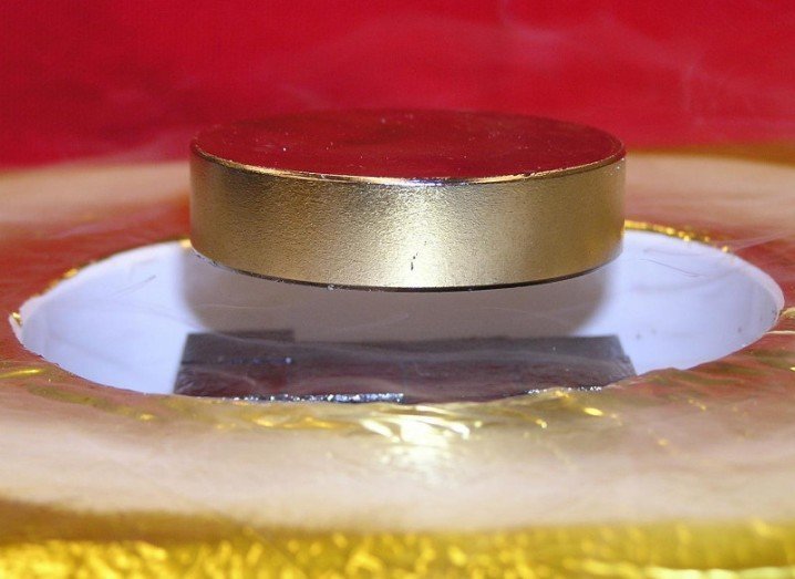 This image of a magnet levitated over a high-temperature superconductor array shows rectangular TFMs (black) levitating a heavy ferromagnet (silver) above a container of liquid nitrogen, via Weinstein/University of Houston
