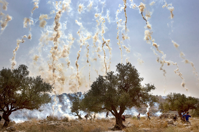 Israeli soldiers shoot tear gas during a demonstration against Israel's controversial separation barrier in the West Bank village of Nilin – image via Cris Toala Olivares, documentary single image winner at Magnum and LensCulture Photography Awards 2016