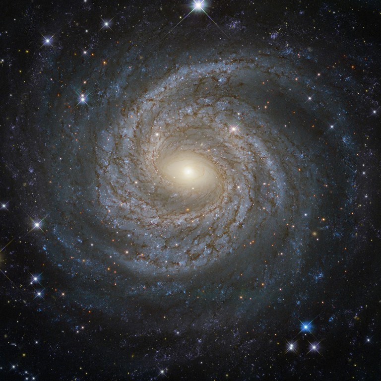 Called NGC 6814, this ‘face-on’ image flattens out the galaxy, with a luminous nucleus, “spectacular sweeping arms” and dark dust rippled throughout. NASA says this galaxy enjoys a particularly bright nucleus, which is probably why this image is so clearly estimated – the brightness is a “telltale sign that the galaxy is a Seyfert galaxy”. Image: ESA/Hubble & NASA