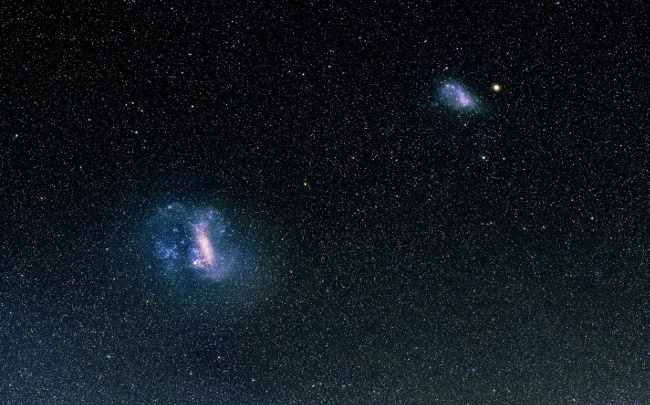 The Magellanic Clouds in the night sky. The Large and the Small Magellanic Clouds are visible. The Clouds are moving towards the bottom left corner. Image: V. Belokurov and A. Mellinger