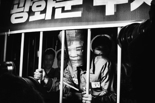 Behind Bars. “Imprisoned and surrounded by journalists, a protester plays President Park Geun-hye during the Christmas Eve demonstration in Seoul, South Korea.” Image: Argus Paul Estabrook. Street Series Winner, Magnum and LensCulture Photography Awards 2017.