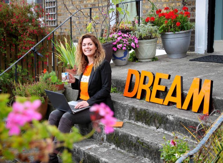 Vanessa Tierney of Abodoo sits on steps beside a sign that says 'Dream'.