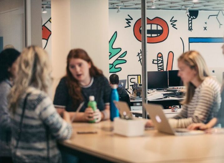 A group of young Intercom employees sit at table chatting.