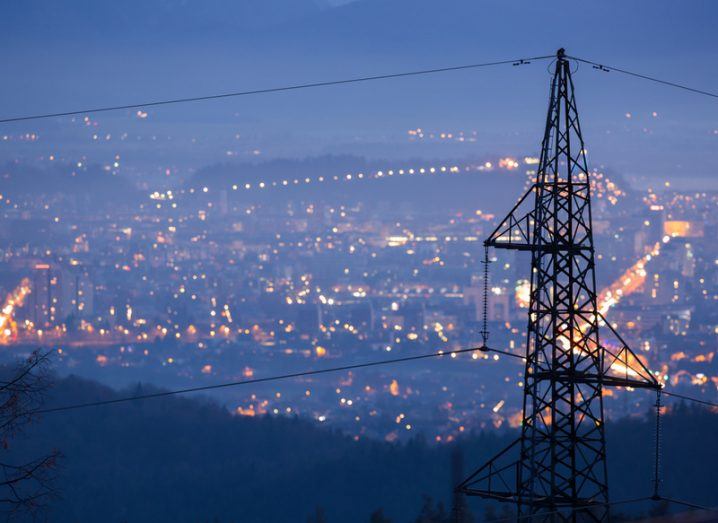 image of electricity pylons over a city at night time