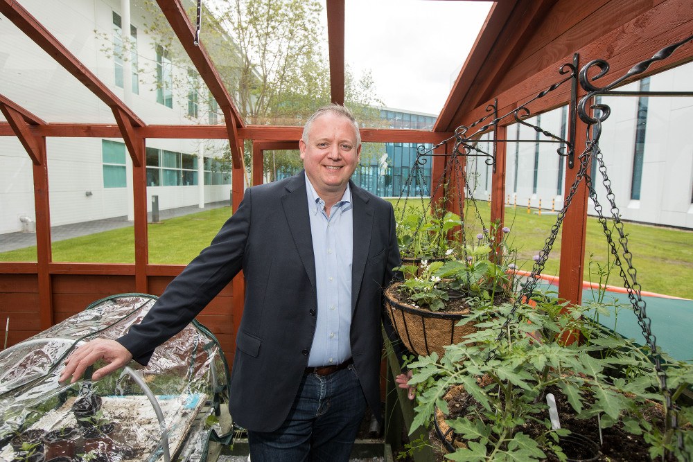 Niall O'Leary poses for a photograph amid plants growing in the greenhouse on the Regeneron site