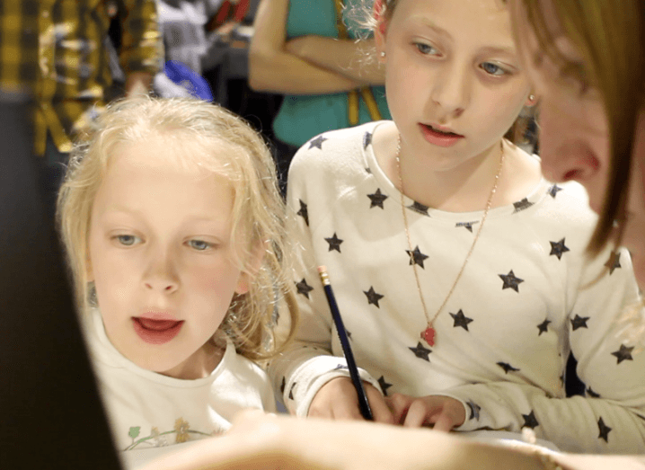 Sisters Robyn and Cara look on intently as Amy Neale from Mastercard explains how they can crack the code