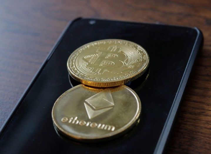 3D representation of a bitcoin and an ether coin on top of a smartphone