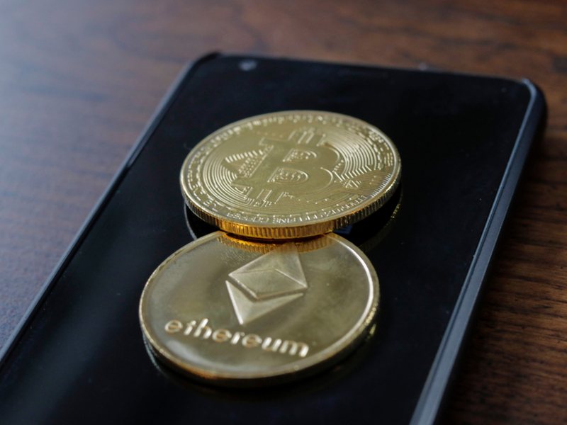 3D representation of a bitcoin and an ether coin on top of a smartphone