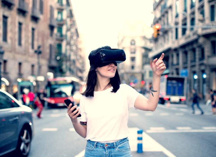 developer wears virtual reality googles in a modern urban city controls it with smartphone