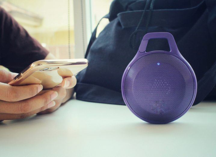 Bluetooth speaker beside a woman using a mobile phone