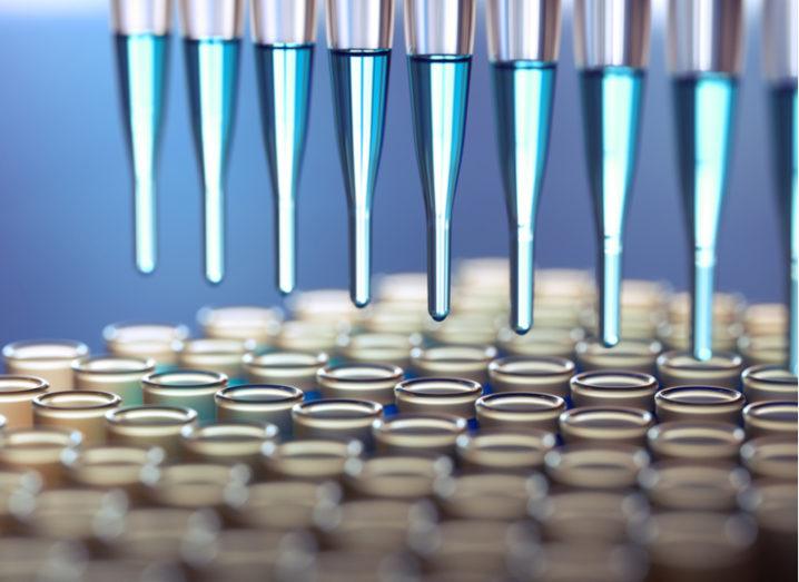 Close-up of a number of dispensers placing liquid samples into a series of test tubes.