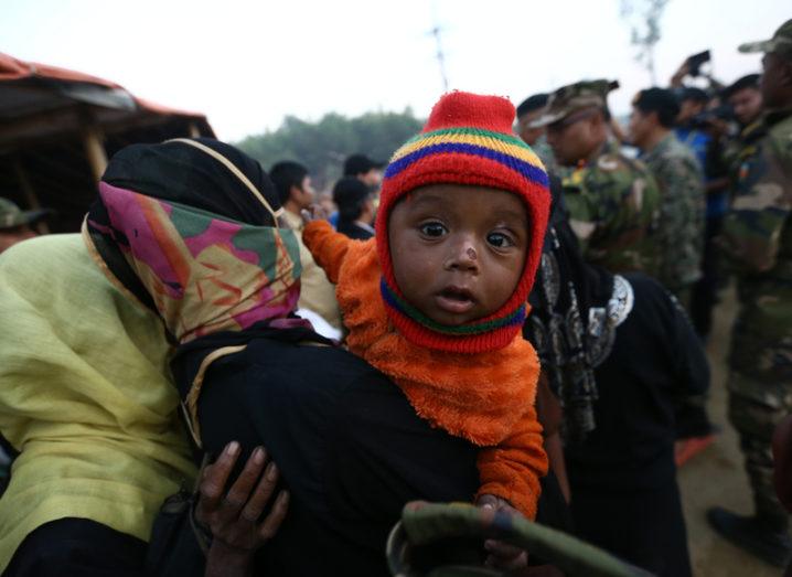 A Rohingya baby in a carrier on someone's back at a refugee camp in Bangladesh.