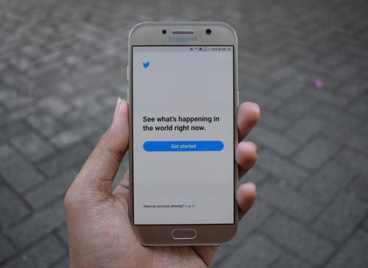 Hand holding a Samsung phone with the Twitter app open.