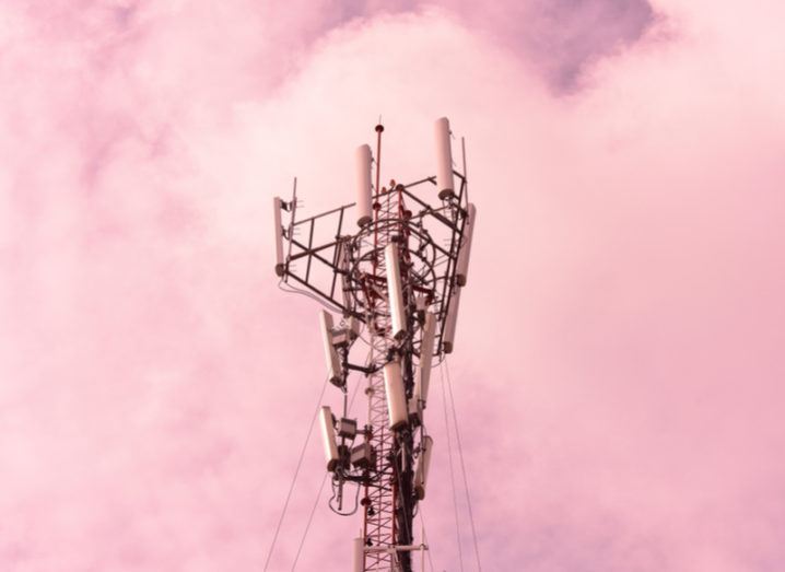 A mobile communications tower against a pink cloudy sky.