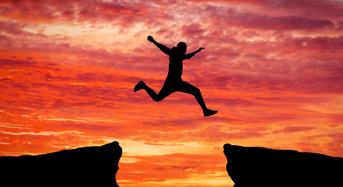 Man jumping over chasm against ruby sunset. Is the tech talent gap actually getting worse with time?