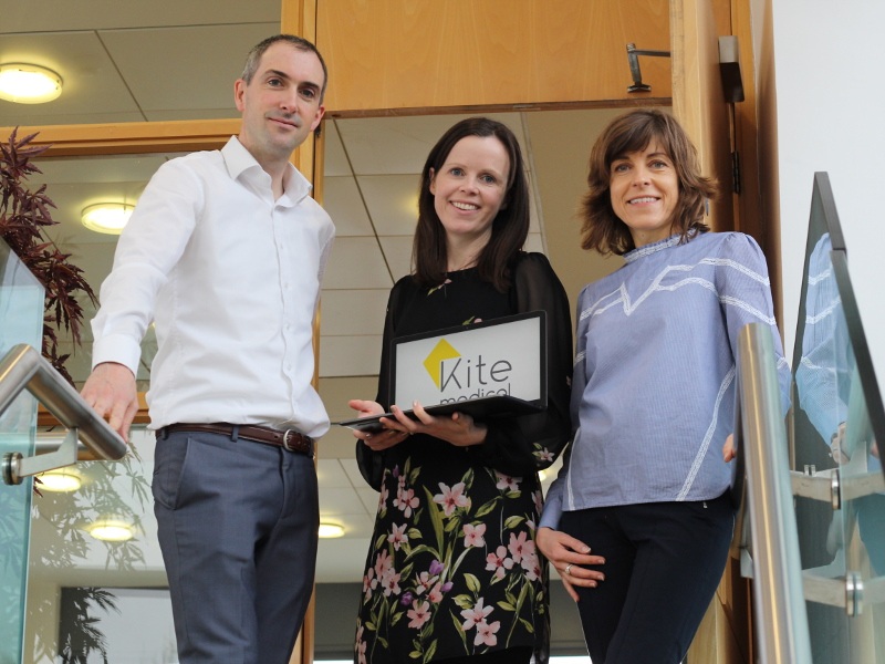 Man and two women at top of a stairs.