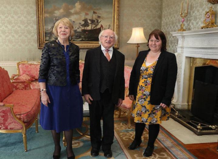 Two women and the President of Ireland in a formal meeting room.