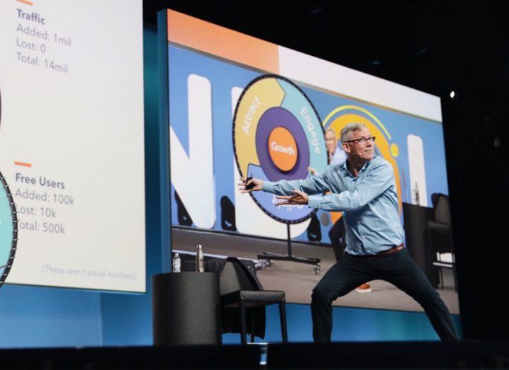 Man standing on a stage pointing to a presentation.