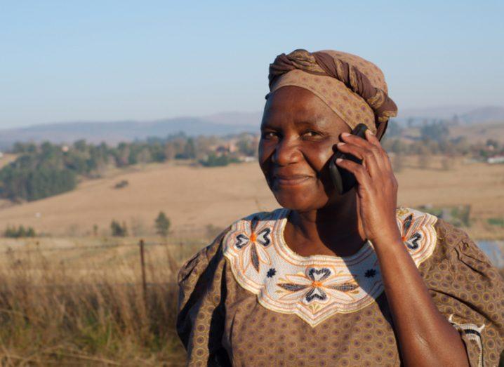 Traditional African Zulu woman speaking on mobile cell phone telephone in rural KwaZulu-Natal.