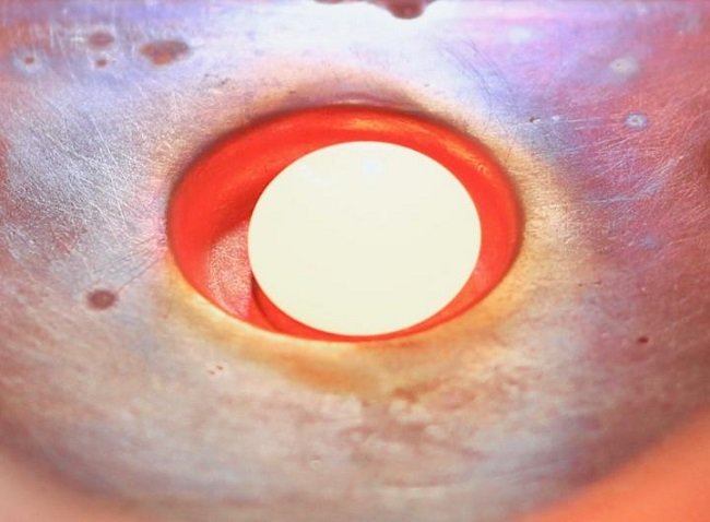 A glowing hot sphere of a new material in a steel vacuum arc melter. 