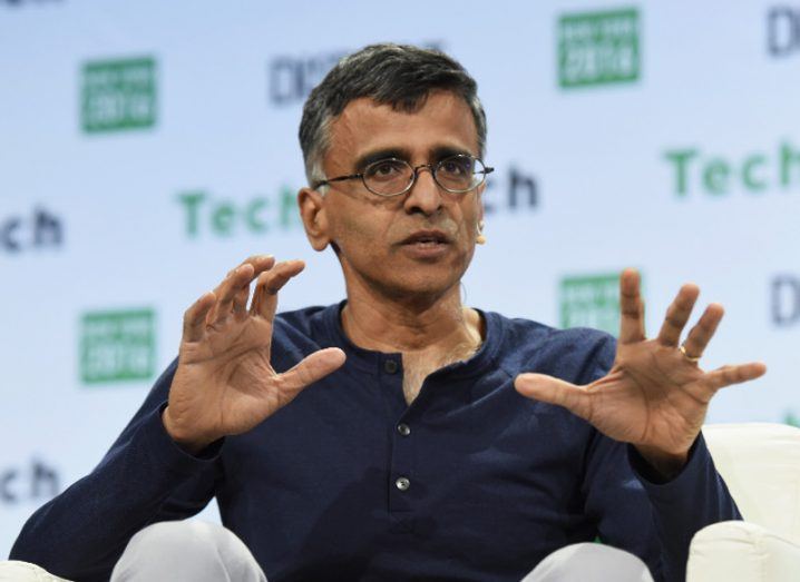 Man in glasses in navy jumper gesturing with his hands in reply to a question at a tech conference.