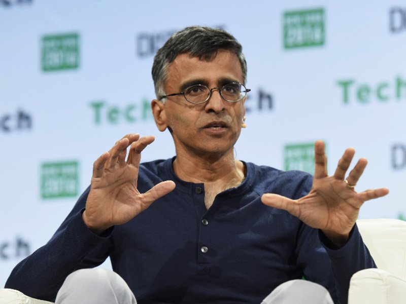 Man in glasses in navy jumper gesturing with his hands in reply to a question at a tech conference.