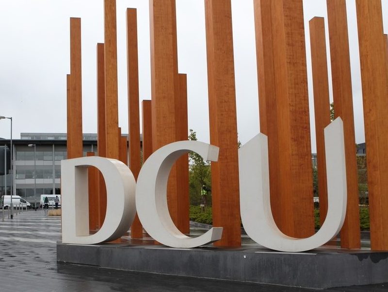 DCU campus featuring a sculpture of the letters 'DCU' with yellow poles behind it.