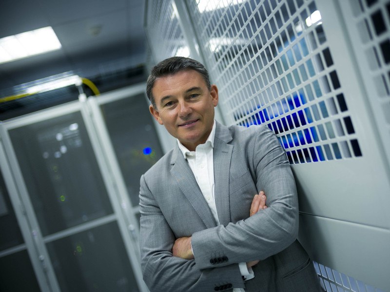 Man in grey suit pictured standing in data centre.