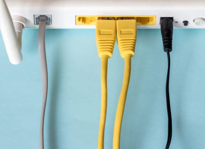 Top-down photo of a Wi-Fi router with colourful cables on a blue background.