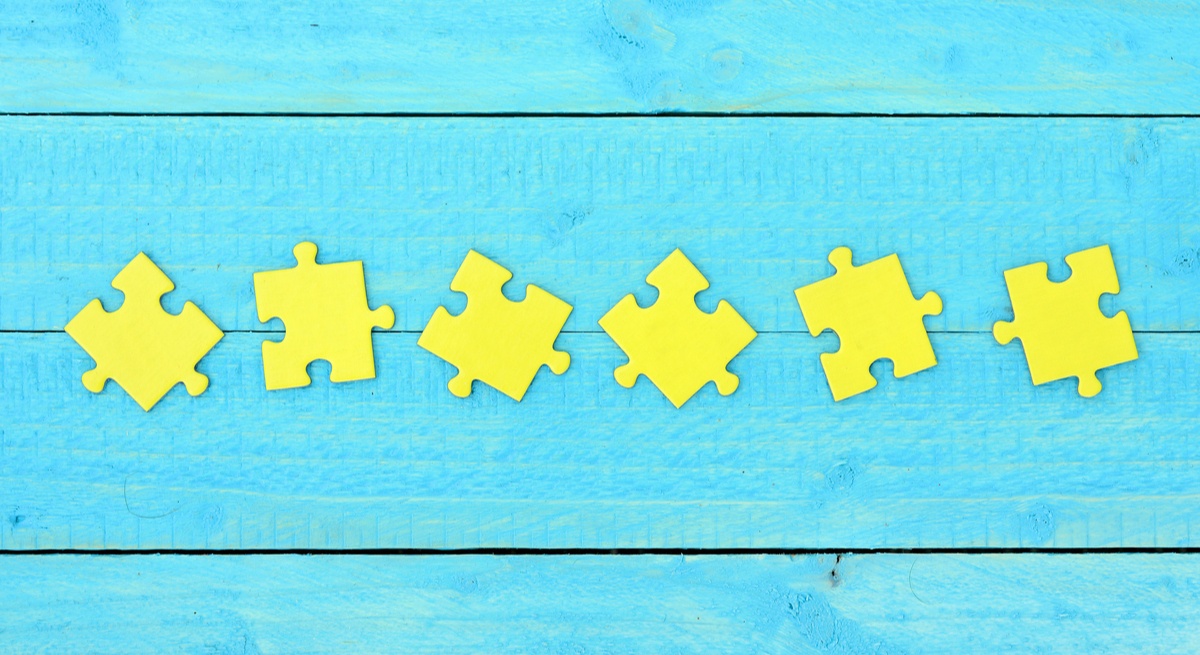 Six yellow jigsaw pieces arranged on a sky-blue wooden background.