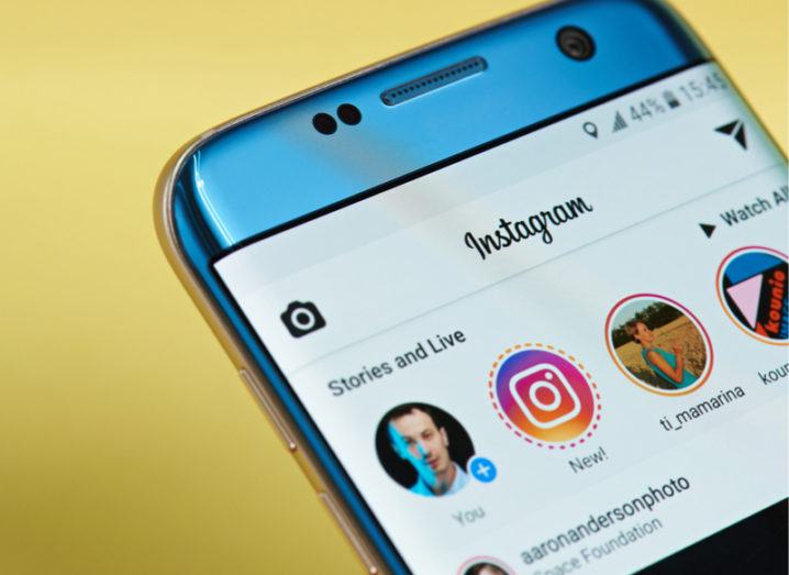 Mobile phone showing Instagram home screen with buttons to view Stories. Yellow background.