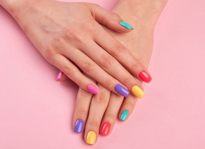 Hands with multi-colour nail polish on a salon table.
