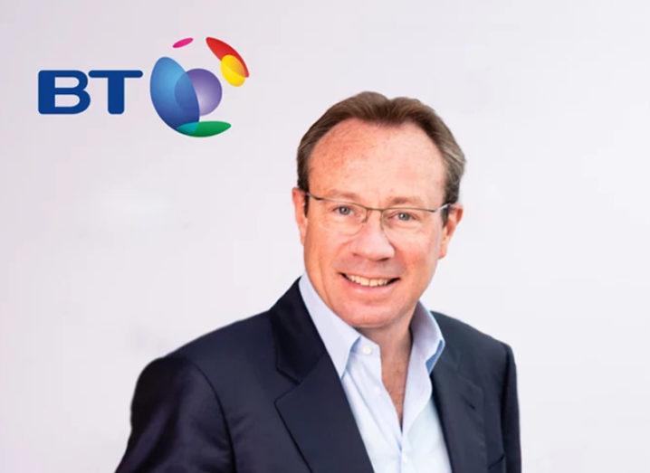 Man in navy jacket and white shirt stands in front of a BT logo.