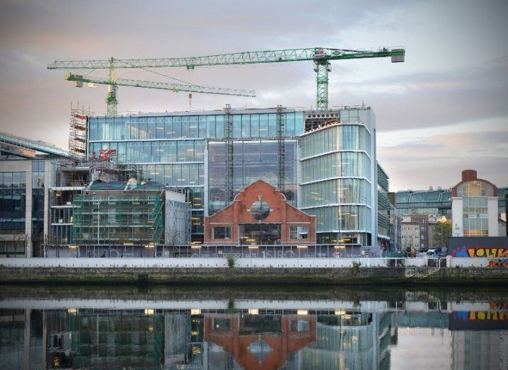 A shiny glass office development with construction towers on south quays of Dublin.