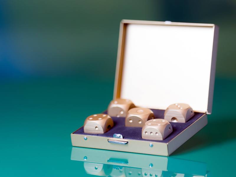 A slim hinged box opened wide to reveal five dice set in purple velvet casing.