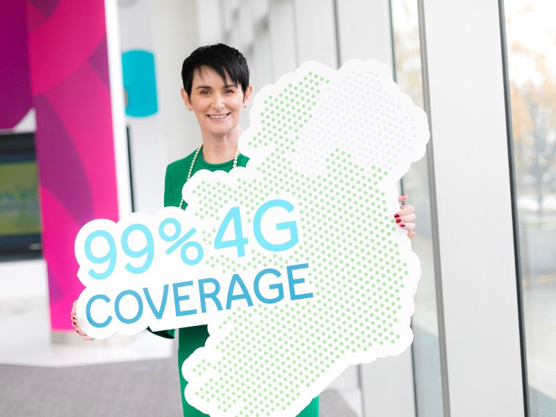 Woman with black hair and green dress holds an image of Ireland with the words 99pc 4G coverage.