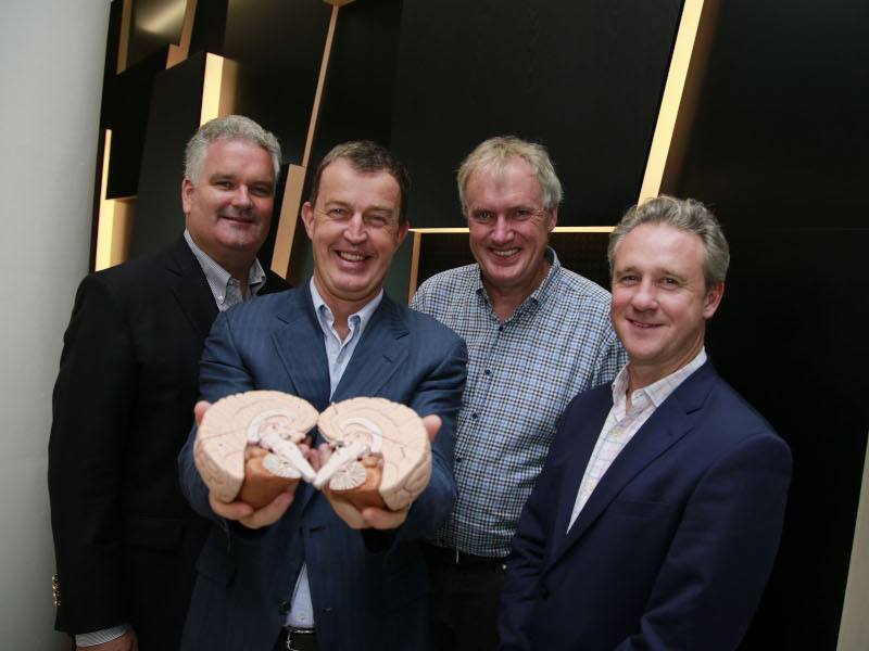 Four men with one holding medical model of brain.