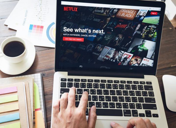 Netflix login page open on a laptop screen with hands typing.