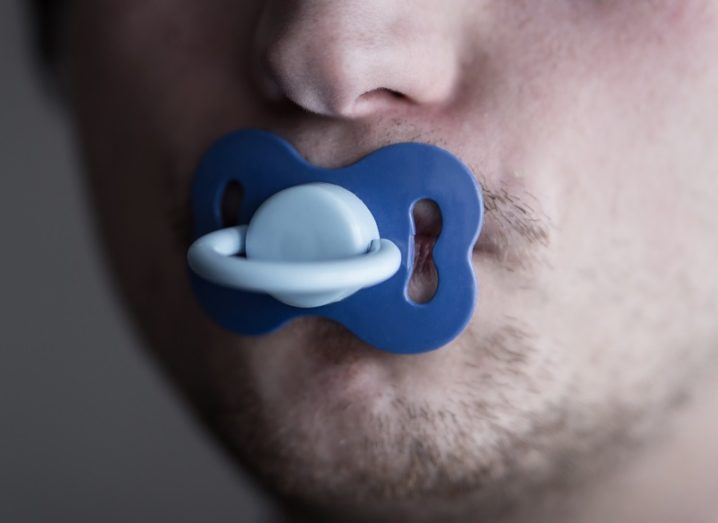 Close-up of a man's face with a soother in his mouth.