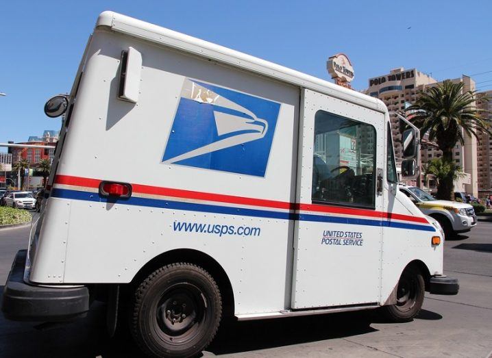 A parked, white USPS truck in a driveway.