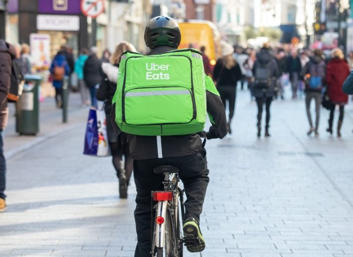 An Uber Eats cyclist seen from behind on the street, wearing a branded bag.