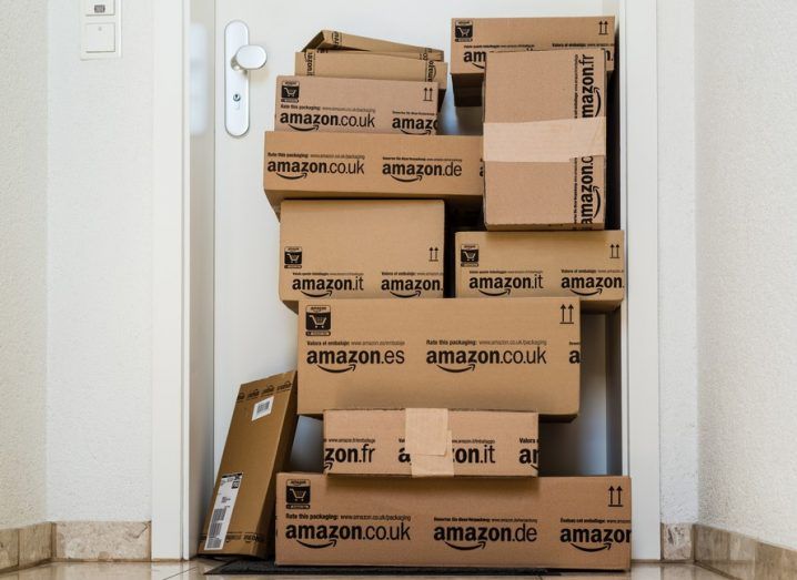 A large stack of parcels by Amazon.com in different sizes is awaiting its customer in front of an entrance door of a flat.