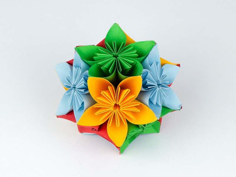 Origami flower in multiple colours on white background.