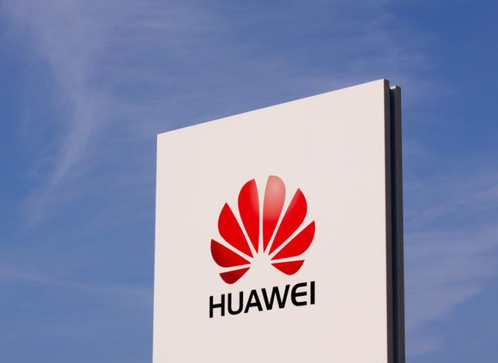 Picture of a Huawei logo on a sign under a blue sky.