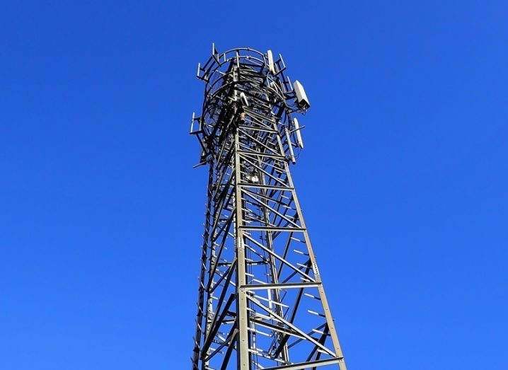 A mobile phone mast with a bright and cloudless blue sky in the background.