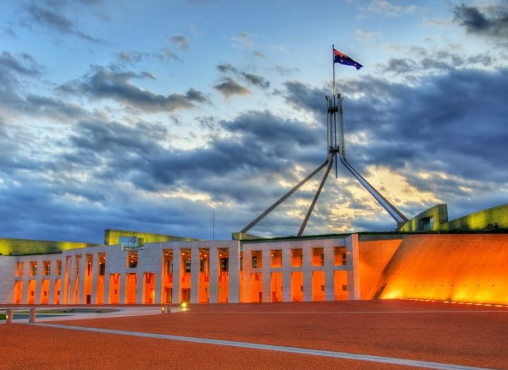 Parliament House in Canberra, Australia at sunset, with dark clouds in the sky.